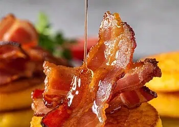 Best Savoury Mielie Crumpets with Crispy Bacon - Saffarazzi Stack of golden cornmeal pancakes topped with crispy bacon and a drizzle of maple syrup.