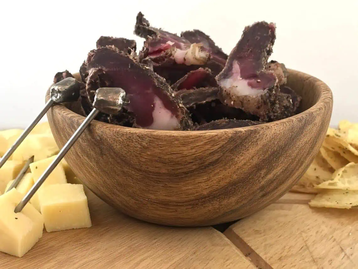 Beef and game biltong recipe - Saffarazzi Sliced beef and game biltong served in a wooden bowl with cheese and crisps.