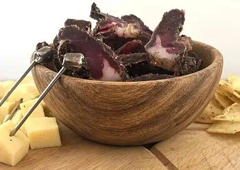 Beef and game biltong recipe - Saffarazzi Sliced beef and game biltong served in a wooden bowl with cheese and crisps.