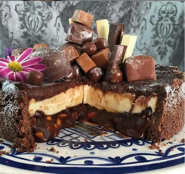 Slice of salted caramel and chocolate cheesecake with peanut caramel and chocolate topping