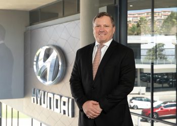 Hyundai executive standing beside logo at dealership showroom