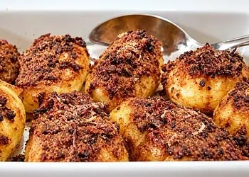 Roast Potatoes with Biltong - Saffarazzi Golden roast potatoes topped with grated biltong in a white baking dish