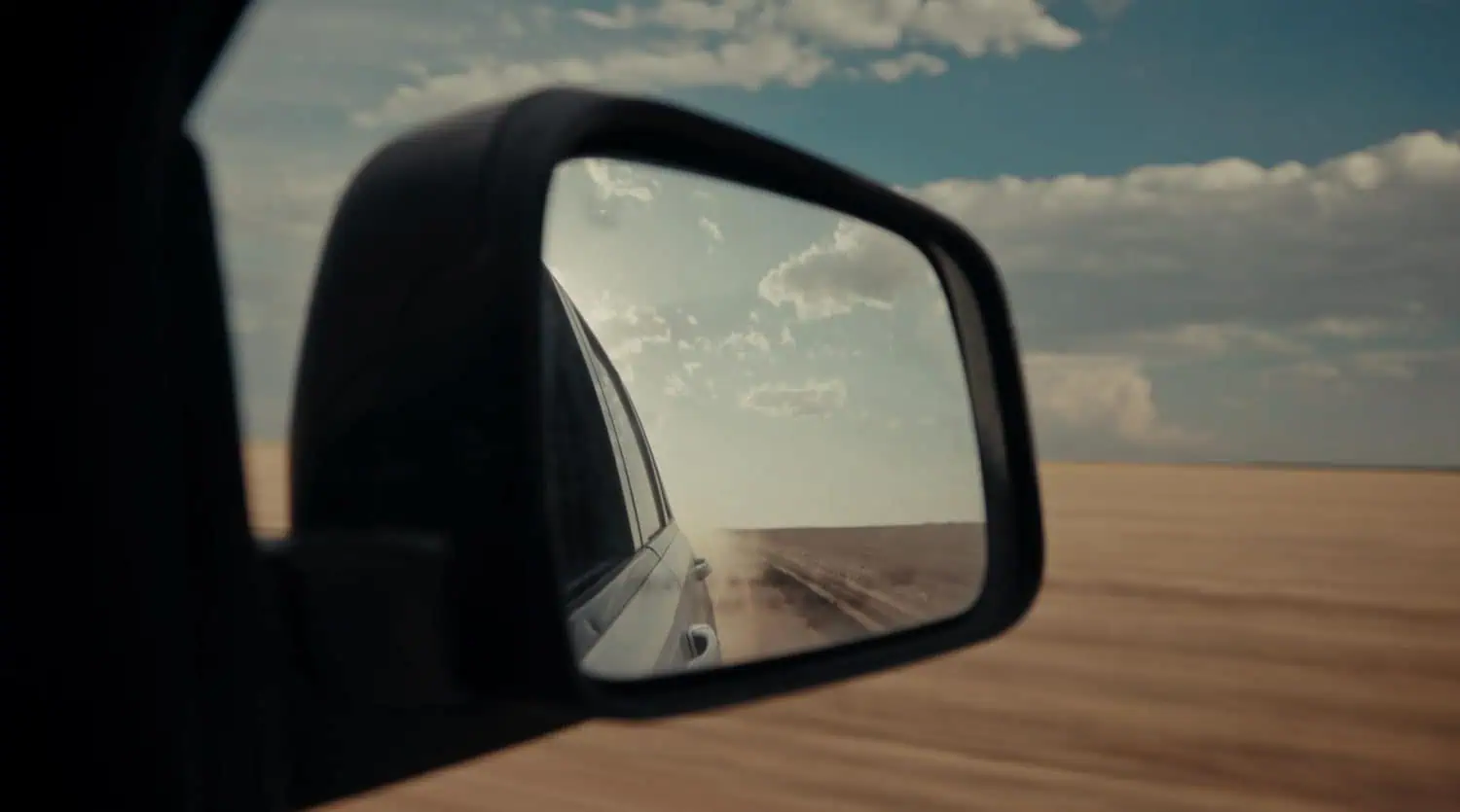 Side mirror view of a Ford vehicle on dusty road - Saffarazzi Side mirror view of a Ford vehicle on dusty road
