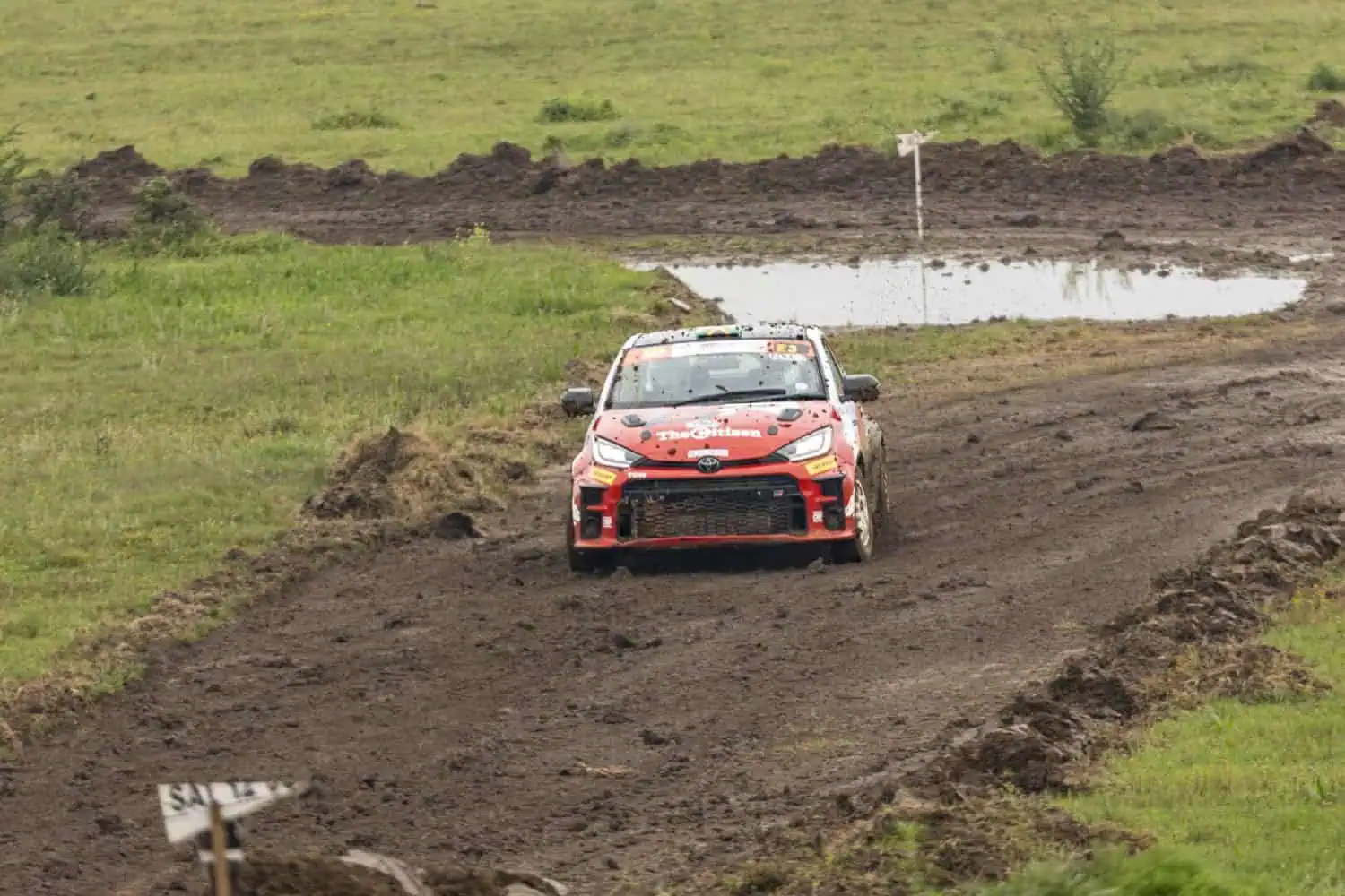Toyota GR Yaris rally car on muddy track past puddle - Saffarazzi Toyota GR Yaris rally car on muddy track past puddle