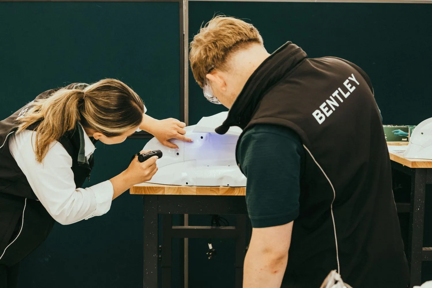 Bentley apprentices inspecting white component with UV torch - Saffarazzi Bentley apprentices inspecting white component with UV torch