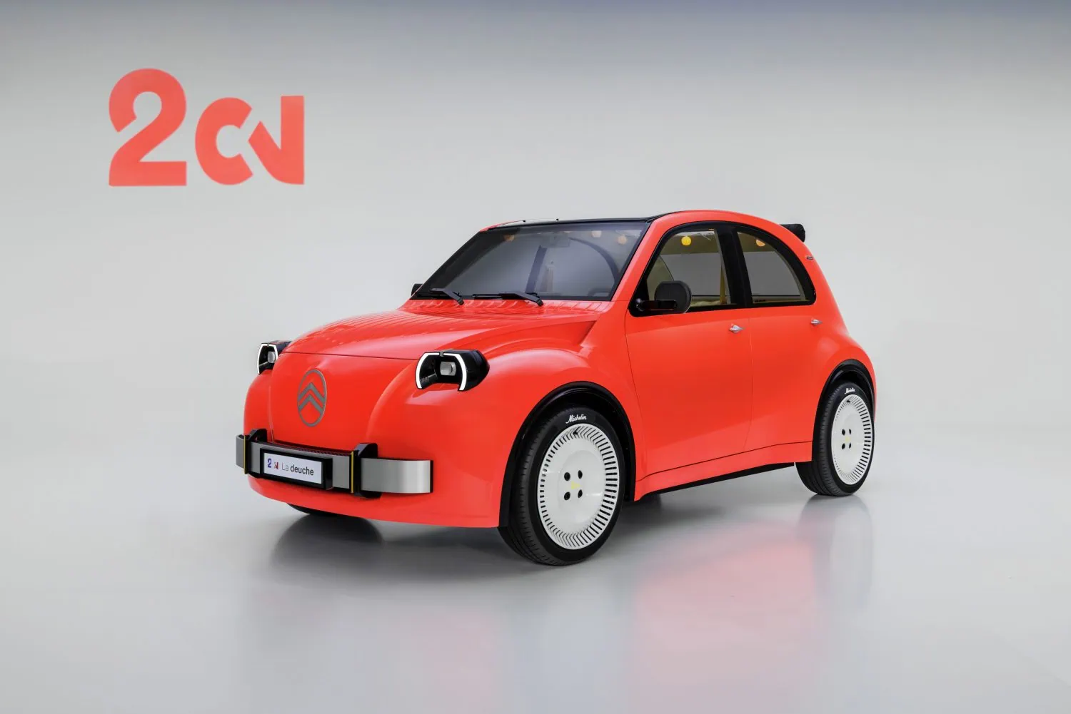Citroën 2 CV Concept front three-quarter view from left - Saffarazzi Red compact car in a studio with a large red '2CV' logo on the wall behind it, left side visible in the frame.