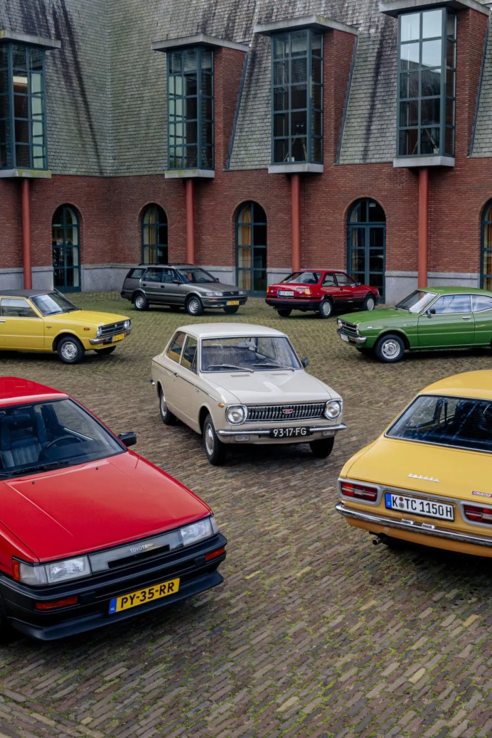 Corollas in brick courtyard - Saffarazzi Classic Toyota Corolla models arranged in a courtyard.