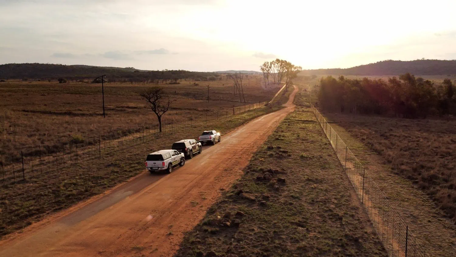 Convoy of bakkies on a dirt road at sunset - Saffarazzi Convoy of bakkies on a dirt road at sunset