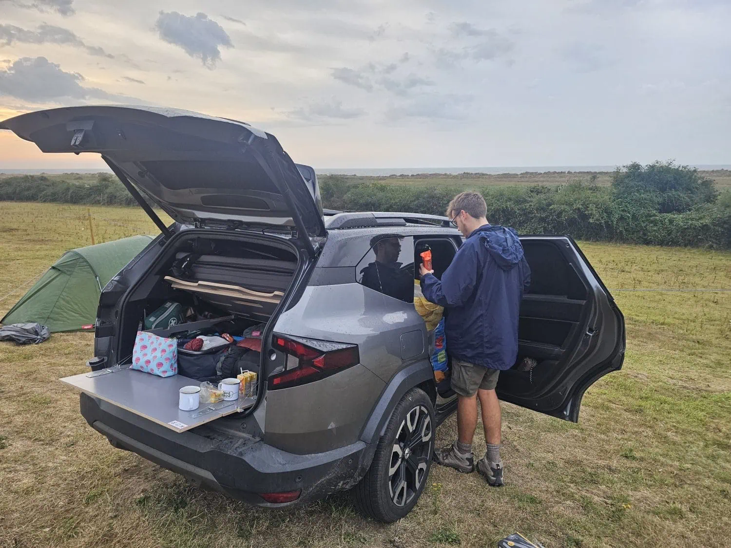 Dacia Bigster with boot table set up at a coastal campsite - Saffarazzi Dacia Bigster with boot table set up at a coastal campsite