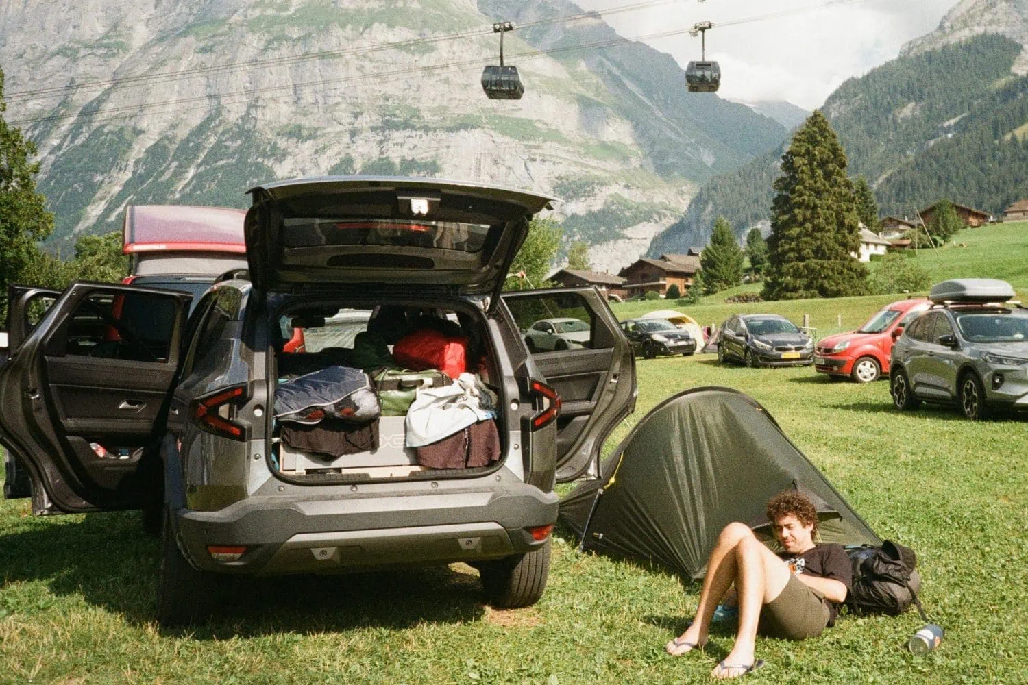 Dacia Bigster with open doors beside a tent at a campsite - Saffarazzi Dacia Bigster with open doors beside a tent at a campsite