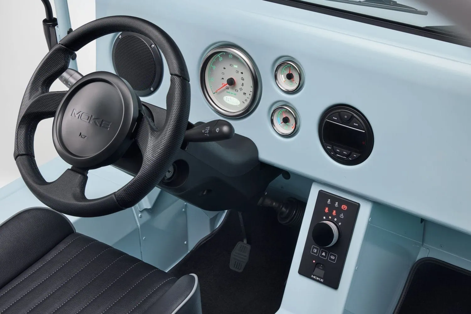 Electric MOKE Mk2 steering wheel and dashboard - Saffarazzi Steering wheel and round gauge cluster inside a light-blue car dashboard with additional controls