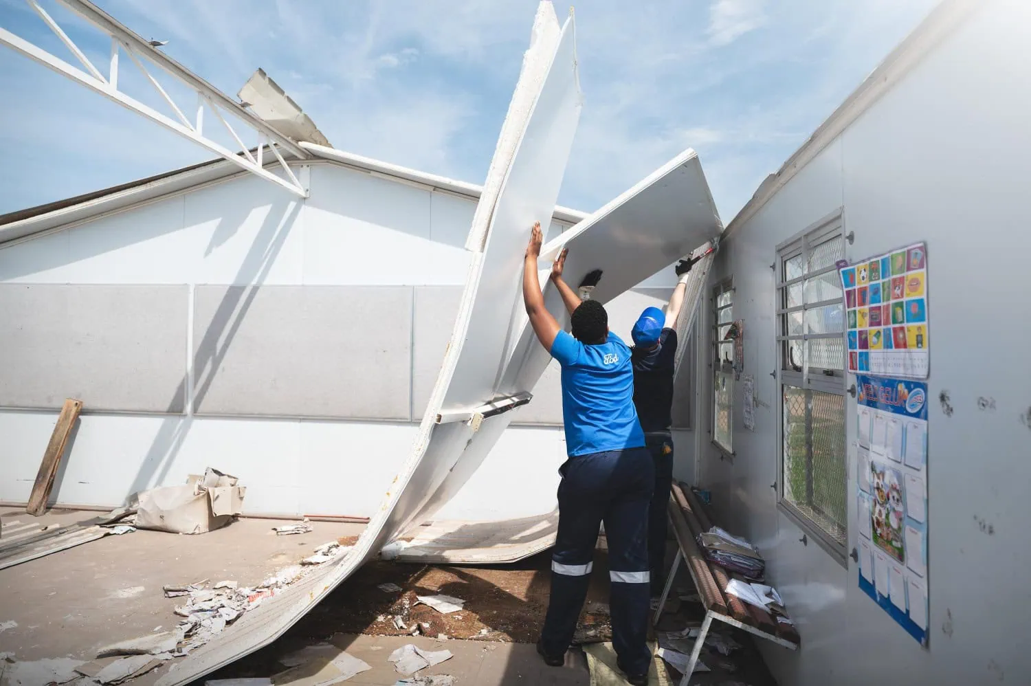 Ford Global Caring volunteers removing damaged school roof panels.