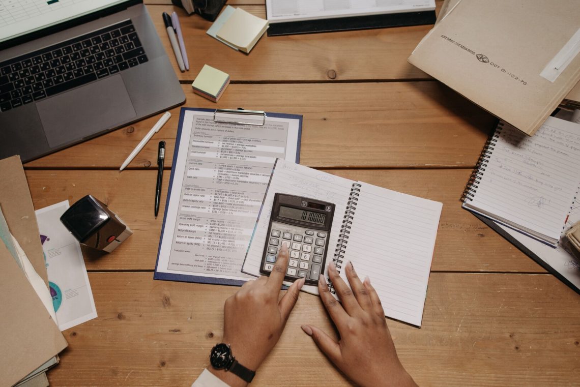 Hands using a calculator over fleet crash cost paperwork - Saffarazzi Hands using a calculator over fleet crash cost paperwork