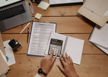 Hands using a calculator over fleet crash cost paperwork