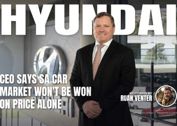 Hyundai executive standing beside logo at dealership showroom