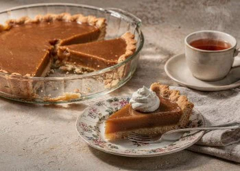 Microwave caramel yoghurt tart with a cut wedge and whipped cream beside a cup of tea