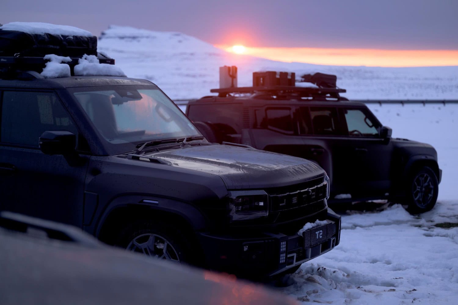 Snow-covered Jetour T2 SUVs parked at sunset.