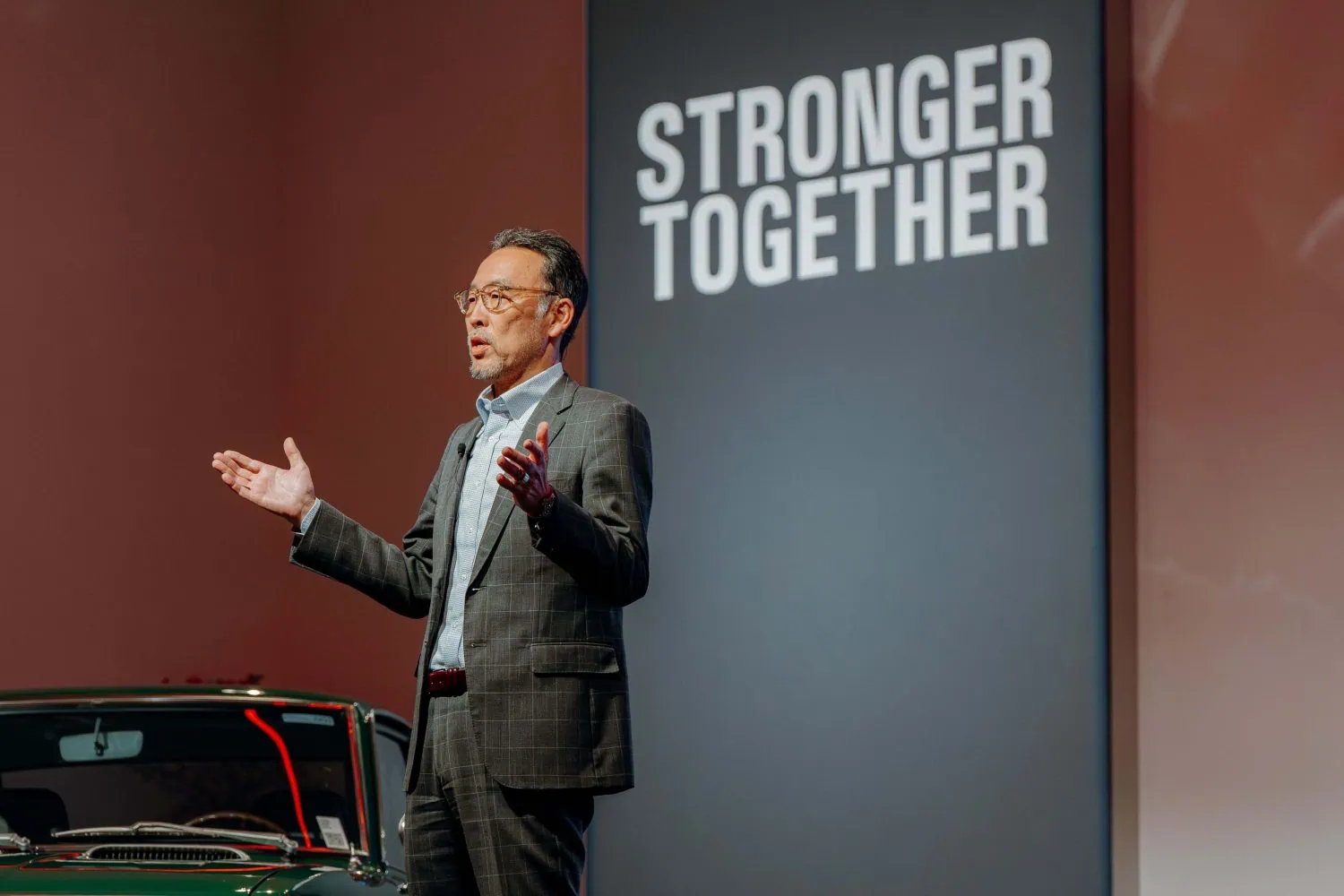 Toyota executive speaking beside Stronger Together sign - Saffarazzi Toyota executive speaking beside Stronger Together sign
