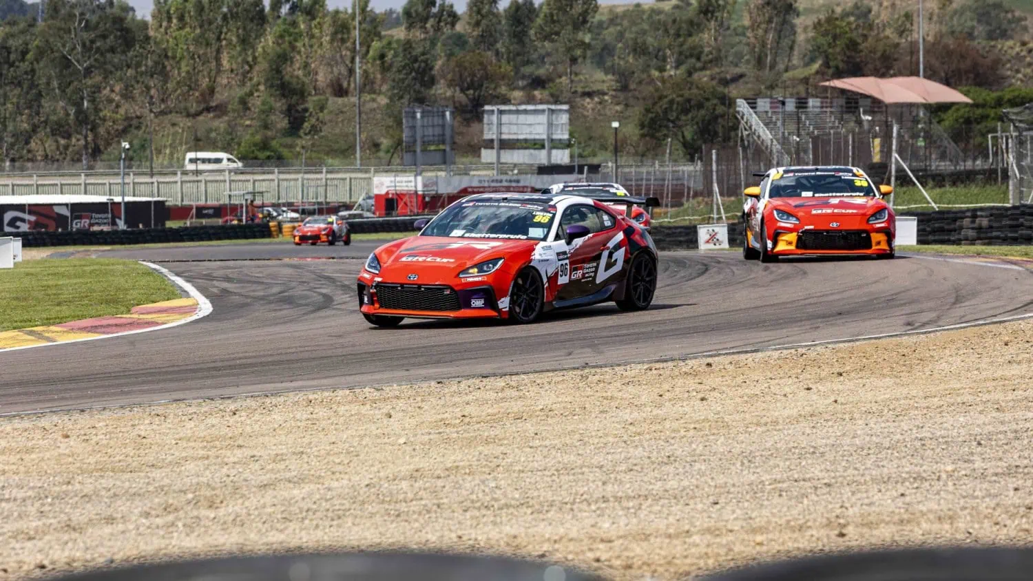 GR86 group through bend - Saffarazzi Toyota GR86 cars exiting a bend in a group.