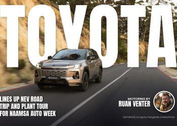 Silver Toyota RAV4 driving on a winding mountain road beside a rocky cliff and trees in the background.