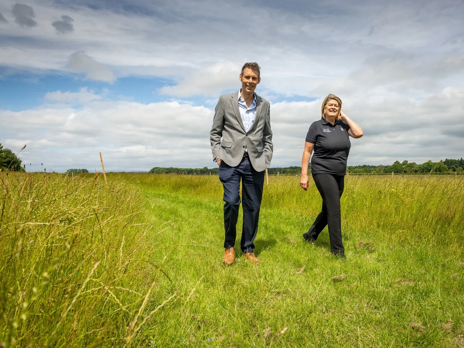 Walkers in Goodwood meadow - Saffarazzi Two people walking through a Goodwood Estate meadow.