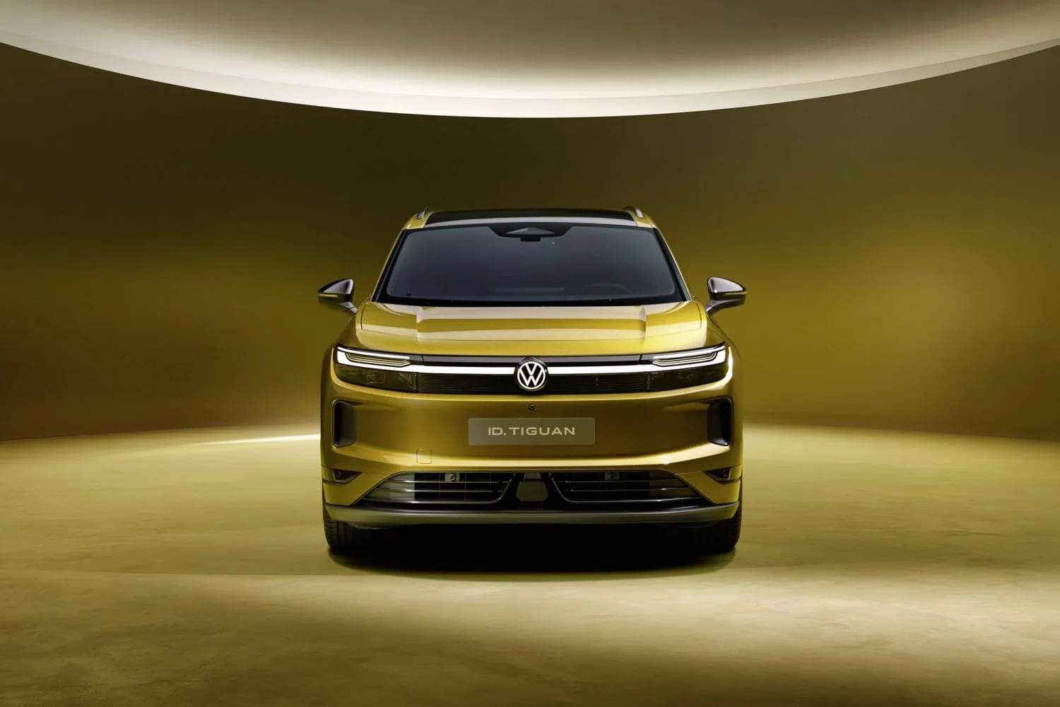 Volkswagen ID. Tiguan electric SUV front view - Saffarazzi Front view of a yellow VW ID. Tiguan SUV in a warm, illuminated showroom.