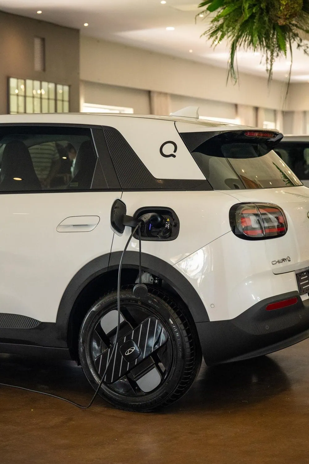 White Chery Q charging indoors, rear three-quarter view - Saffarazzi White Chery Q charging indoors, rear three-quarter view